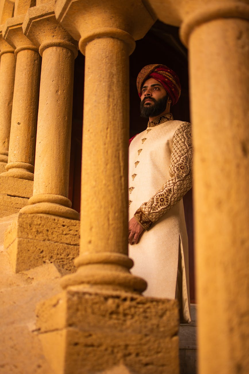 indian sikh man in turban standing behind ancient colonnade